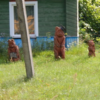 Три деревянных медведя охраняют сельский дом.