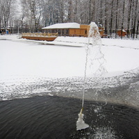 Пруд в парке зимой с фонтанчиком