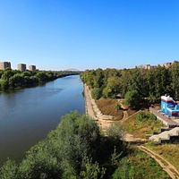 Река Москва в Воскресенске между Новлянскими мостами. Вид с пешеходного моста на автомобильный. Справа - детский аттракцион.