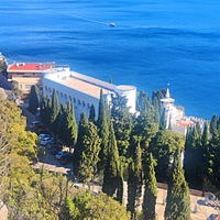 Вид на Черноморское побережье с Царской тропы. Дворец Кичкине (летняя резиденция князя Д. К. Романова) на территории санатория "Кичкине" ФСО РФ в п.г.т. Гаспра.  Далее - строения отеля "Пальмира Палас".