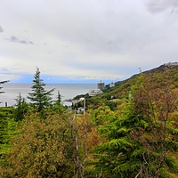 Вид с Алупкинского шоссе в Нижней Ореанде на Черноморское побережье п.г.т. Курпаты: корпус "Дружба" комплекса «Курпаты» («летающая тарелка»), строящийся 14-и этажн. апарт-комплекс «Царский Берег»", высотный ЖК "Южная Пальмира", вверху - Стройгородок.