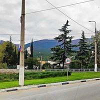 Въезд в Ялту по Южнобережному шоссе, за ним - панорама главной гряды Крымских гор: слева - восточная часть Ай-Петринского массива (Никитская яйла), в центре и правее - горный амфитеатр, частью которого является гора Пендикуль.