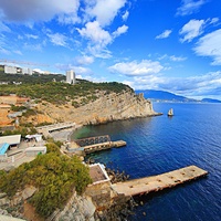 Вид со смотровой площадки замкового комплекса "Ласточкино гнездо" на вершине Аврориной скалы на побережье мыса Ай-Тодор с действующей и строящейся инфраструктурой и его восточный (Лимен-Бурун) отрог с отдельной маленькой скалой Парус.