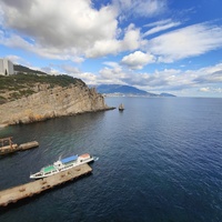 Вид со смотровой площадки с балюстрадой у западной стены замка "Ласточкино гнездо" на вершине Аврориной скалы на окружающую акваторию и восточный (Лимен-Бурун) отрог с отдельной маленькой скалой Парус мыса Ай-Тодор.