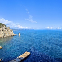 Вид со смотровой площадки во внутреннем дворе замкового комплекса "Ласточкино гнездо" на вершине Аврориной скалы на псевдоготический замок, окружающую акваторию, побережье и восточный (Лимен-Бурун) выступ мыса Ай-Тодор с маленькой скалой Парус.