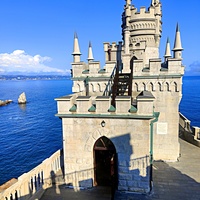 Вид с барбакана (сооружение перед замком с верхней см. площадкой) на псевдоготический замок "Ласточкино гнездо" с входной башней, мерлоны и пенакли (готические зубцы и угловые башенки на фасадах и донжоне) и на верхний ярус донжона (главной башни).