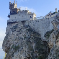 Вид с подножия Аврориной скалы (среднего отрога Монастыр-Бурун) мыса Ай-Тодор на псевдоготический замок "Ласточкино гнездо" и балюстраду смотровой площадки внутреннего двора замкового комплекса.