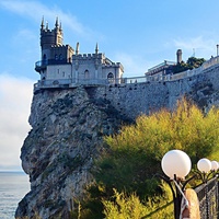 Вид с площадки на склоне Аврориной скалы (среднего отрога Монастыр-Бурун) мыса Ай-Тодор на псевдоготический замок "Ласточкино гнездо" и балюстраду смотровой площадки внутреннего двора замкового комплекса.