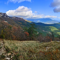 Вид с Кореизской тропы на склоны Ай-Петринской яйлы  перед её вершиной, правее - жилая застройка Ялты на южном склоне главной гряды Крымских гор, перед ней - зелёный конус г. Могаби и акватория Чёрного моря.