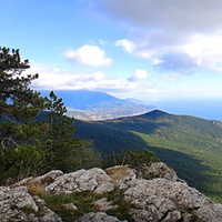 Вид с Кореизской тропы в Ялтинском горно-лесном заповеднике на обрыве перед вершиной Ай-Петринской яйлы на побережье и акваторию Чёрного моря, в центре - зелёный конус г. Могаби, за ним - жилая застройка Ялты.