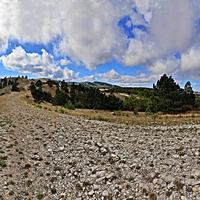 Ай-Петринская яйла вдоль дороги к пос. Охотничье. Слева белые полоски - крутой поворот Бахчисарайского шоссе (дорожный серпантин, "тёщин язык"). Справа - построенный, но не запущенный ветряк без лопастей.