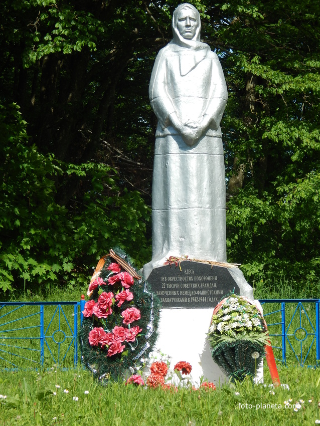 В центре братской могилы скульптура скорбящей женщины. На доске снизу надпись: &quot;Здесь и в окрестностях похоронены 22 тысячи советских граждан, замученных немецко-фашистскими захватчиками в 1942-1944 годах&quot;