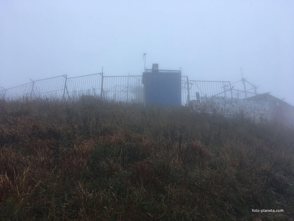 На вершине  горы Большой Тау. Ограждённый объект в/ч 74340 с телекоммуникационным оборудованием на территории ограждения.