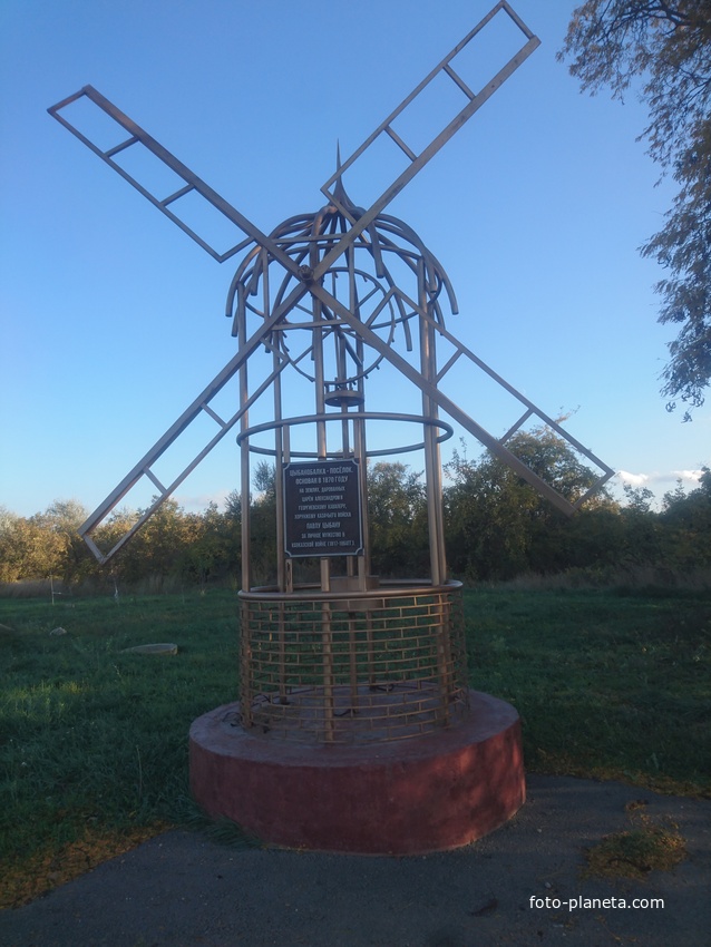 Малая архитектурная форма в виде ветряной мельницы с информацией об основании селения на въезде в село