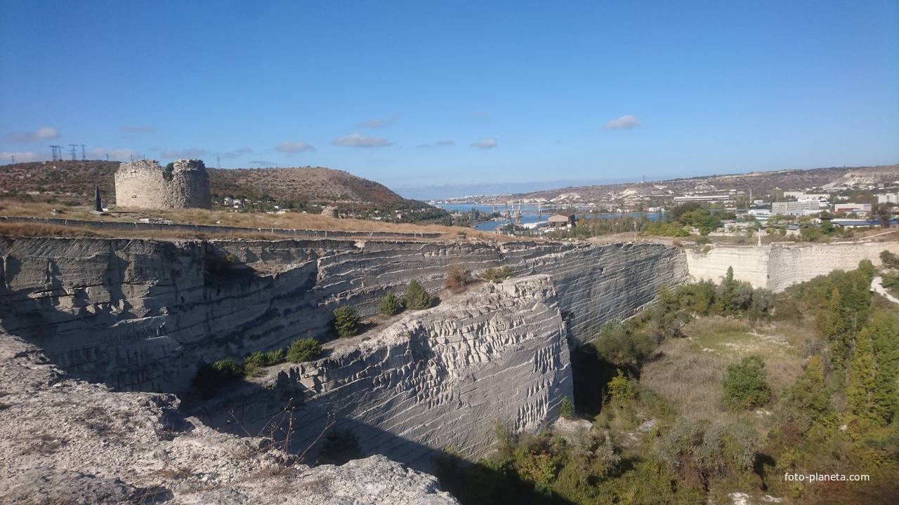 Вид с восточной стороны Монастырской скалы на бывший карьер и остатки башен крепости Каламита. За ними - Зелёная горка и Инкерманская бухта