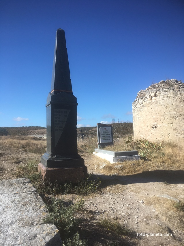 Надгробные плита пулеметчика Дмитриченко, геройски погибшем в 1942г. и обелиск борт-механику Медведеву, погибшему на посту в 1938г. рядом с остатками башни крепости Каламита