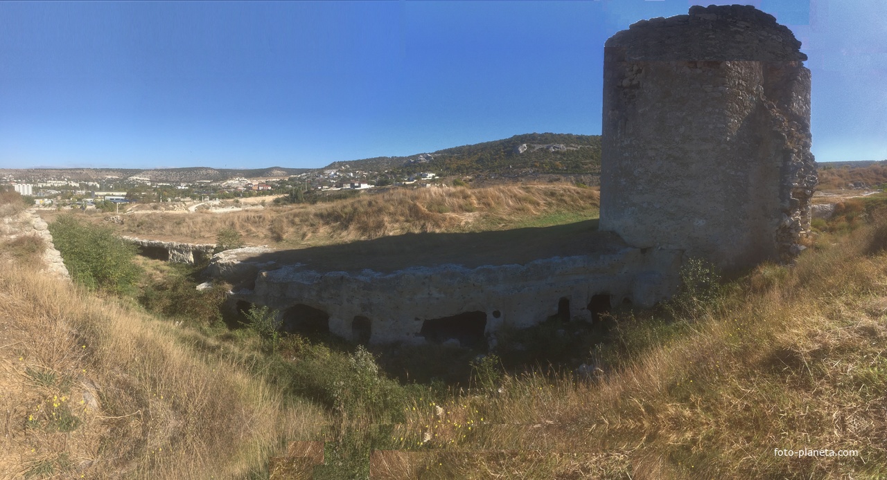 Остатки одной из башен крепости Каламита на вершине юго-западной части Монастырской скалы. К ней примыкает вырубленная в скале траншея с нишами. Далее виден жилой сектор Инкермана у подножия Инкерманских гор и слева за Инкерманом - Мекензиевые горы