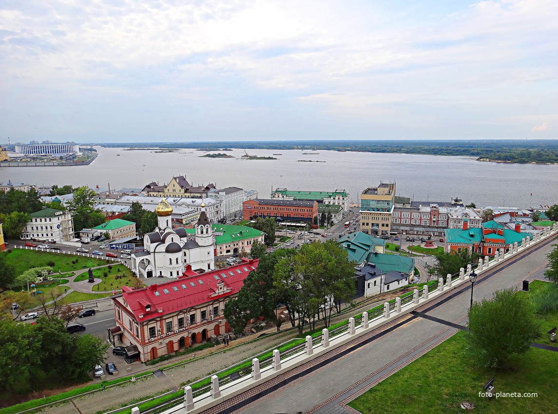Вид с крепостных стен Кремля у Тайницкой башни на городские постройки. В центре левее - Казанский храм, перед ним - бывший доходный дом Бугровых, за ним - стрелка Оки и Волги.