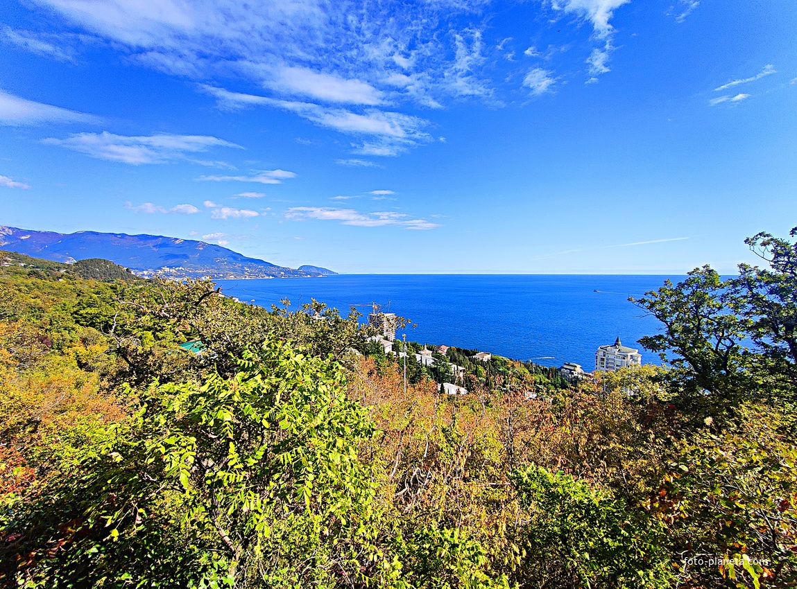 Вид на Черноморское побережье со скалы Утюг. Справа - высотный ЖК "Южная Пальмира", за ним - строящийся 14-и этажный апарт-комплекс «Царский Берег»", перед ними - корпуса и столовая с клубом, а слева - зелёная крыша бассейна санатория "Горный".