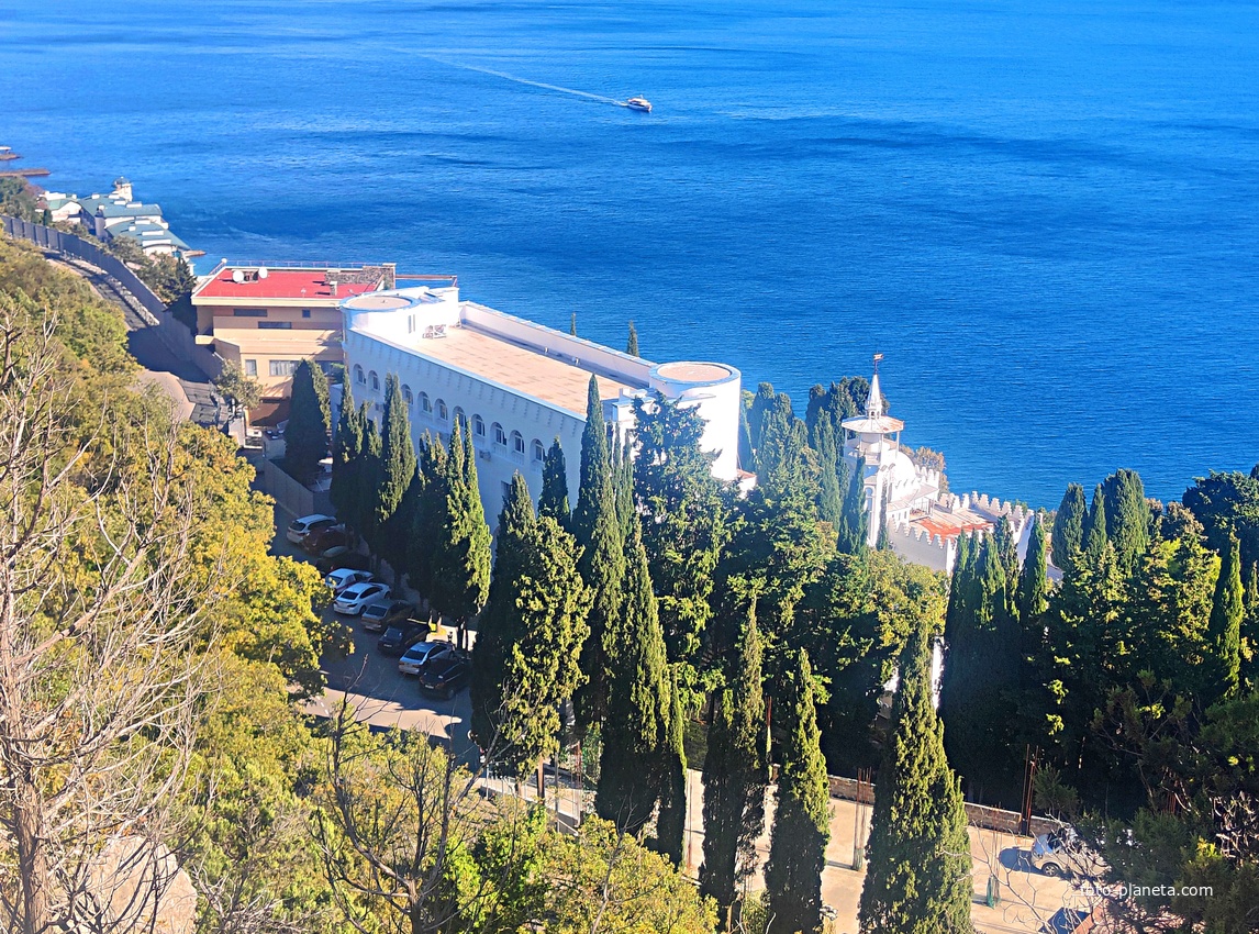 Вид на Черноморское побережье с Царской тропы. Дворец Кичкине (летняя резиденция князя Д. К. Романова) на территории санатория "Кичкине" ФСО РФ в п.г.т. Гаспра.  Далее - строения отеля "Пальмира Палас".