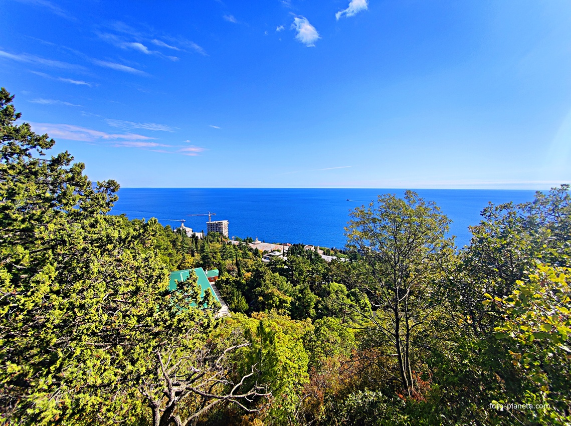 Вид на Черноморское побережье с Царской (солнечной) тропы. Внизу - корпуса санатория "Горный", здание с большой ротондой - клуб со столовой, с зелёной крышей - бассейн. У берега - строящийся 14-и этажный апарт-комплекс «Царский Берег».