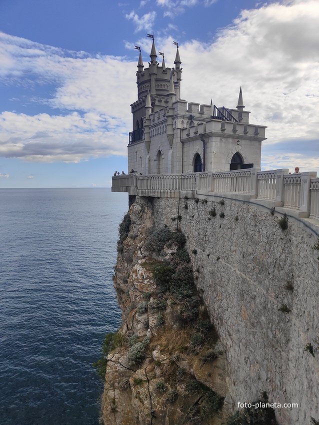Вид со смотровой площадки во внутреннем дворе замкового комплекса "Ласточкино гнездо" на вершине Аврориной скалы на псевдоготический замок и окружающую акваторию.