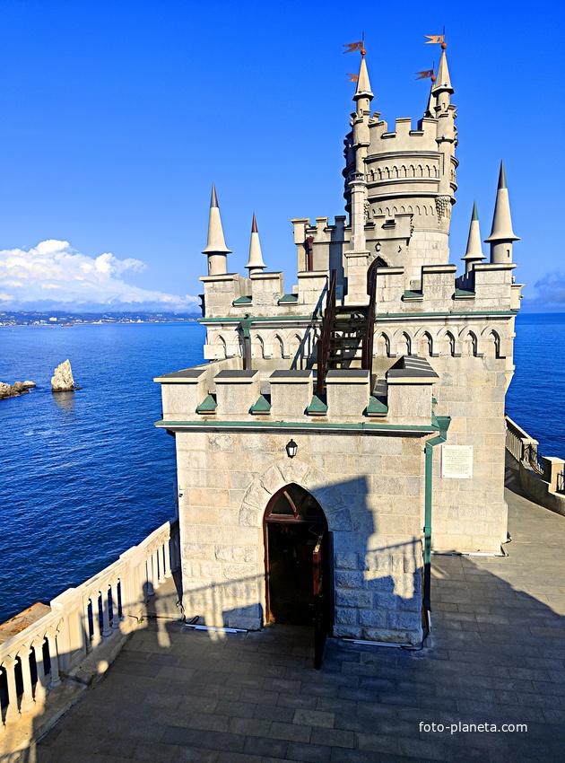 Вид с барбакана (сооружение перед замком с верхней см. площадкой) на псевдоготический замок "Ласточкино гнездо" с входной башней, мерлоны и пенакли (готические зубцы и угловые башенки на фасадах и донжоне) и на верхний ярус донжона (главной башни).