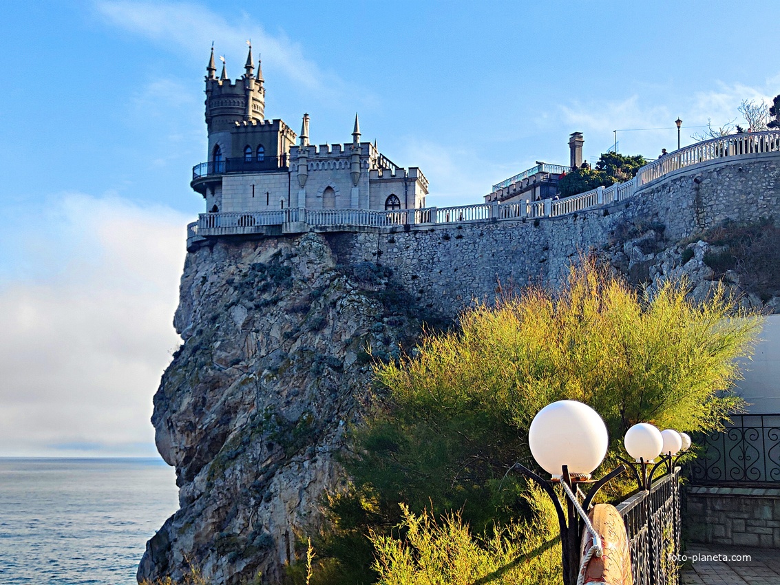 Вид с площадки на склоне Аврориной скалы (среднего отрога Монастыр-Бурун) мыса Ай-Тодор на псевдоготический замок "Ласточкино гнездо" и балюстраду смотровой площадки внутреннего двора замкового комплекса.