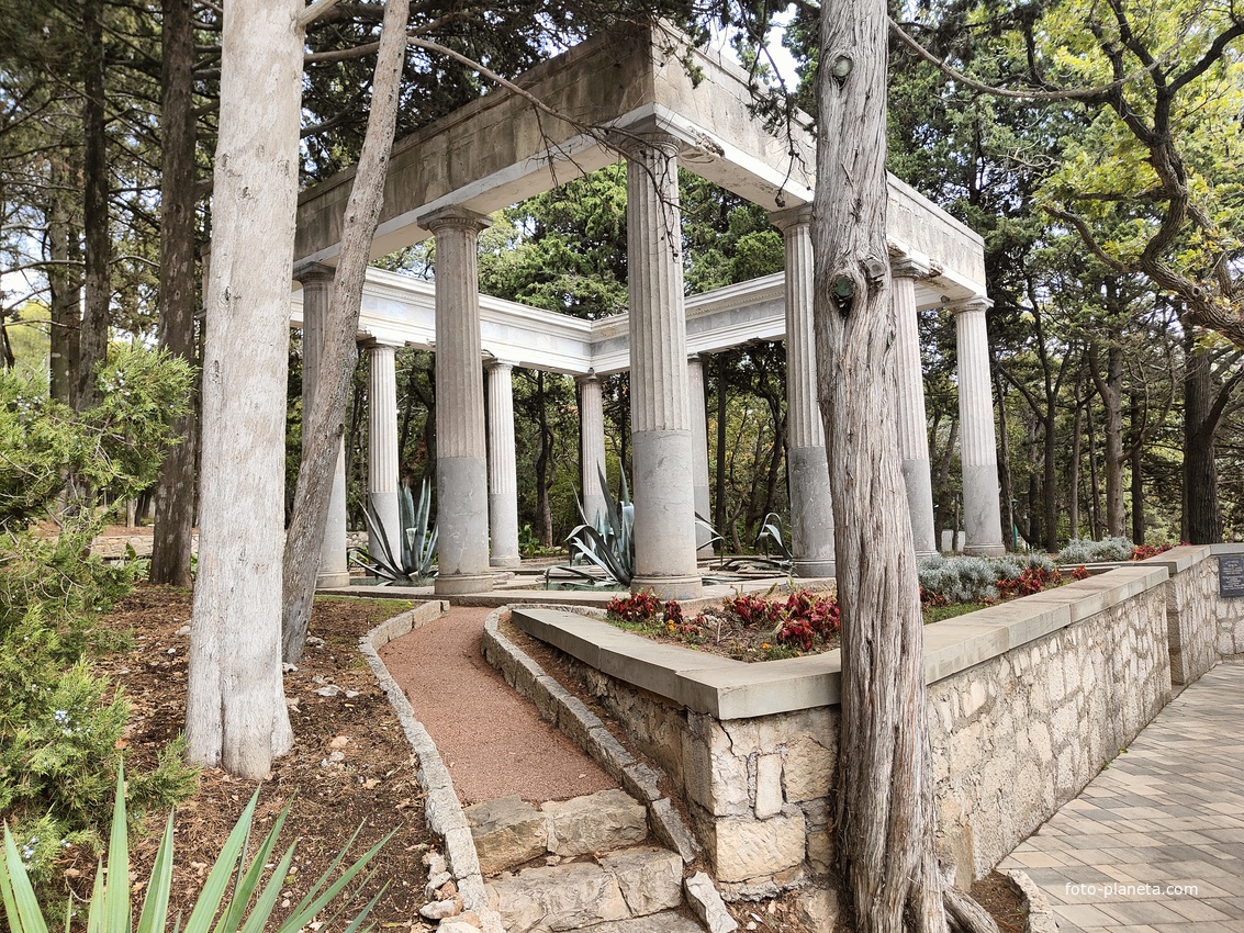 Античная беседка в парке на территории дворца Харакс из 12 мраморных колонн на невысоком стилобате, выполненных в «римском ордере помпейского типа». По одной из версий, это были подлинные  античные элементы, но при послевоенном ремонте были утрачены.