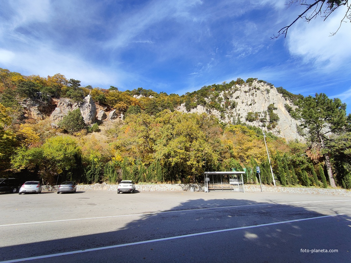 Автостоянка перед храмовым комплексом Архистратига Божия Михаила на Севастопольском шоссе над посёлком Ореанда. Выше - ребро склона горы Ай-Никола с Крестом и Распятием на навершие выступа скалы.