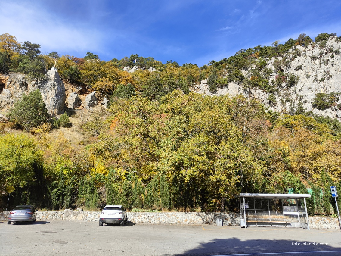 Автостоянка перед храмовым комплексом Архистратига Божия Михаила на Севастопольском шоссе над посёлком Ореанда. Выше - ребро склона горы Ай-Никола с Крестом и Распятием на навершие выступа скалы.