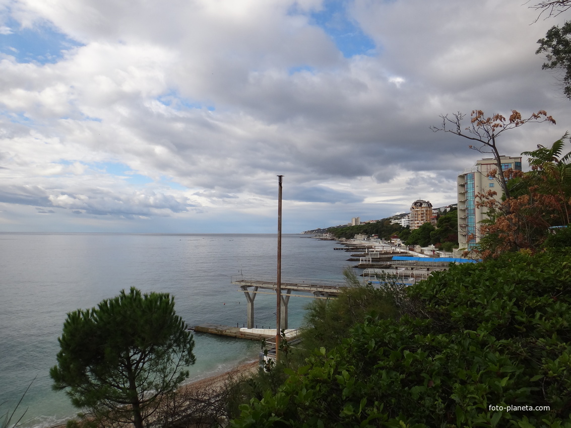 Парк "Дюльбер". Разбит в к. XIX в. Инициатор - велик. князь П. Н. Романов. Проект дворц.-парк. ансамбля с учётом эскизов Романова разраб. ялт. арх. Н. П. Краснов, высажен с участ.  крым. садовода Л. Кремера. Вид на пляж и Черноморскую акваторию.