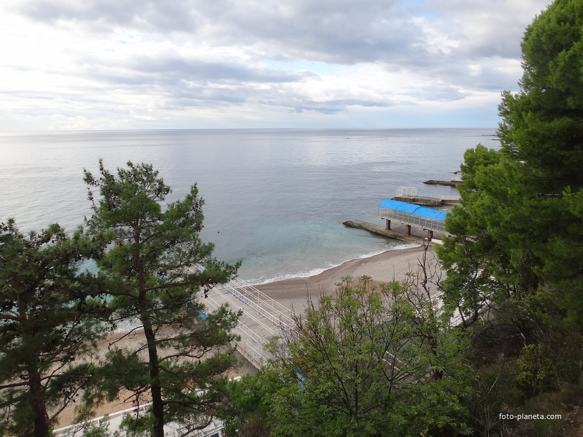 Парк "Дюльбер". Разбит в к. XIX в. Инициатор - велик. князь П. Н. Романов. Проект дворц.-парк. ансамбля с учётом эскизов Романова разраб. ялт. арх. Н. П. Краснов, высажен с участ.  крым. садовода Л. Кремера. Вид на пляж и Черноморскую акваторию.