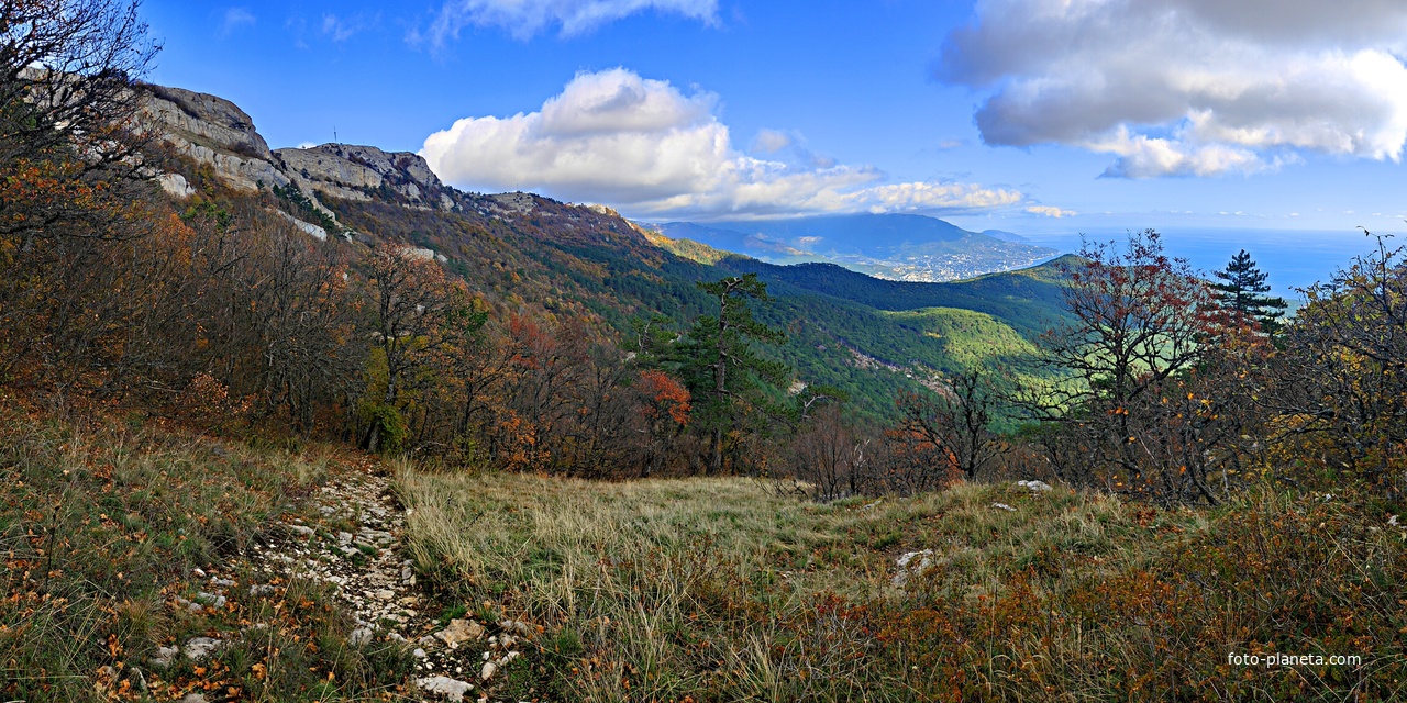 Вид с Кореизской тропы на склоны Ай-Петринской яйлы  перед её вершиной, правее - жилая застройка Ялты на южном склоне главной гряды Крымских гор, перед ней - зелёный конус г. Могаби и акватория Чёрного моря.