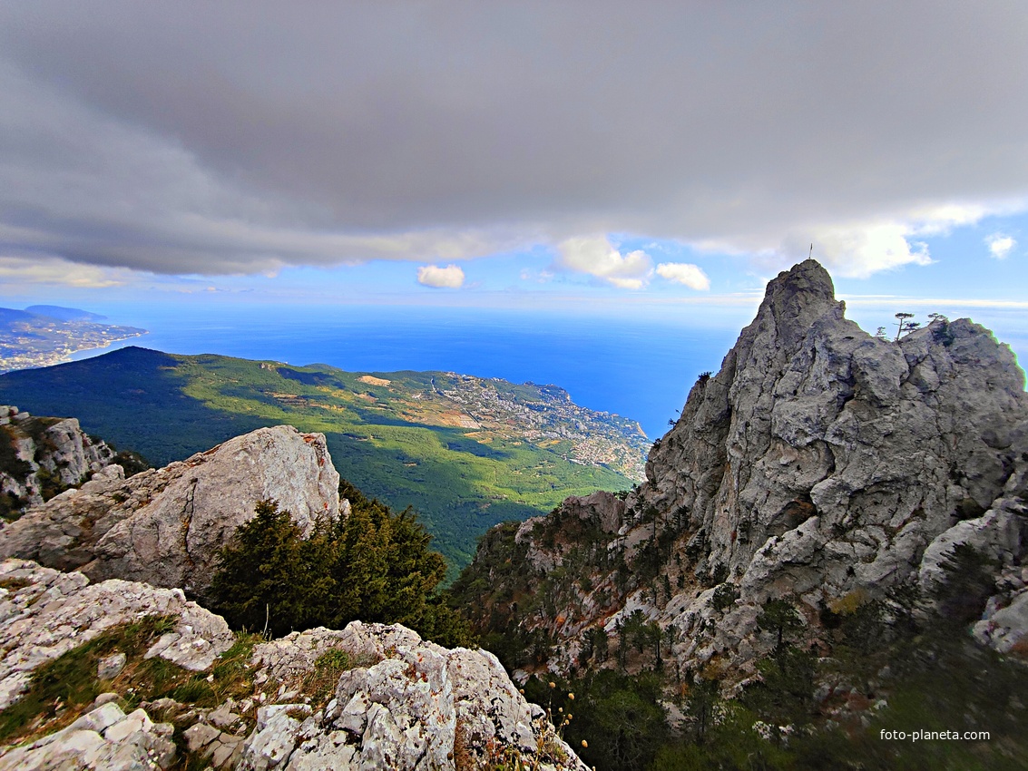 Плато Ай-Петри. Вид на побережье, застройку Гаспры и Кореиза, акваторию Чёрного моря. Справа -  скальный массив с зубцами, слева - зелёный конус г. Могаби.