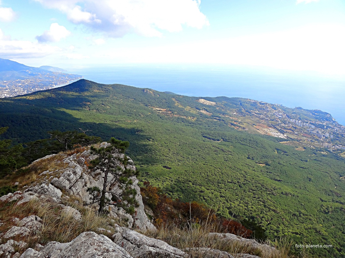 Вид с Кореизской тропы на обрыве перед вершиной Ай-Петринской яйлы на побережье с застройкой Гаспры и акваторию Чёрного моря, слева - зелёный конус г. Могаби, за ним - жилая застройка Ялты.