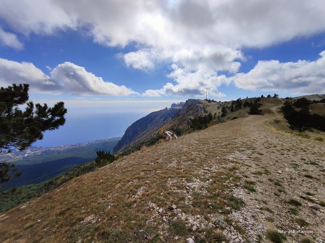 Ай-Петринская яйла вдоль дороги к пос. Охотничье. В центре белые полоски - крутой поворот Бахчисарайского шоссе (дорожный серпантин, "тёщин язык"). Вид на  черноморскую акваторию и побережье с застройкой Кореиза.