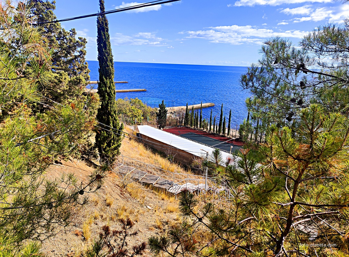 На территории СОСЛ МЭИ "Алушта". Вид с площадки перед жилыми домиками "Стрельбище" на жилой корпус "Бастилия" и теннисный корт за ним.  .