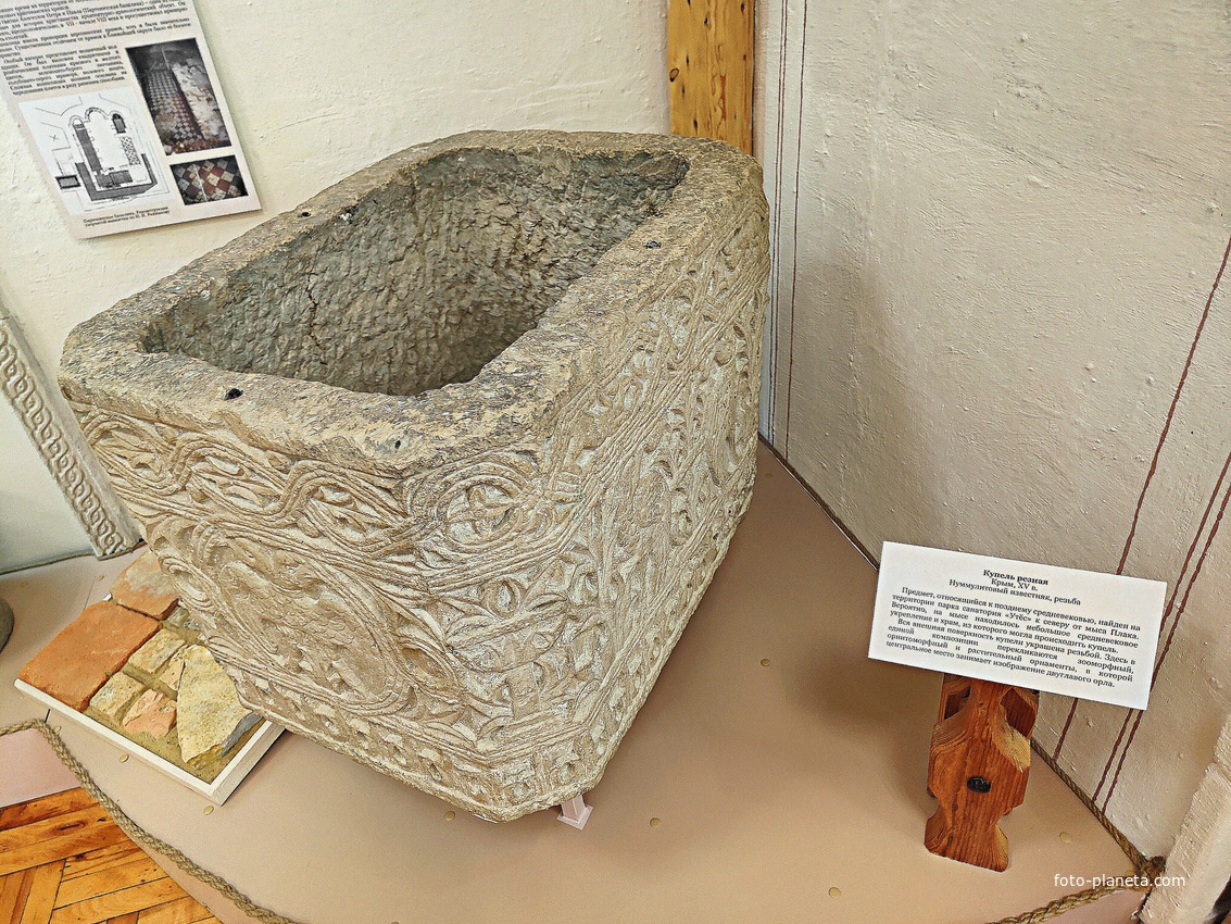 Алуштинский историко-краеведческий музей. Купель резная из нуммулитового известняка, XVв. В композиции перекликаются зоо и орнитоморфный, растительный орнаменты, в центре - изображение двуглавого орла.