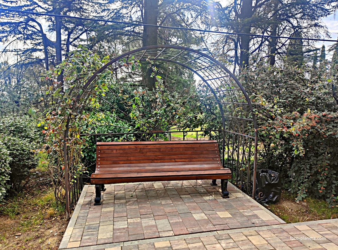 Парк-памятник садово-паркового искусства "Массандровский".  Заложен в 40-х гг. XIX в. Автор первонач. планировки - немецкий садовник К. Кебах. Создан в английском ландшафтном стиле максимальной естественности. Ажурная металлическая арка над лавочкой.