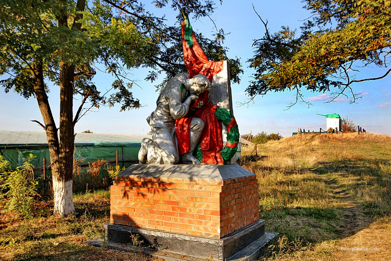 Памятник павшим воинам, справа на заднем плане - братская могила