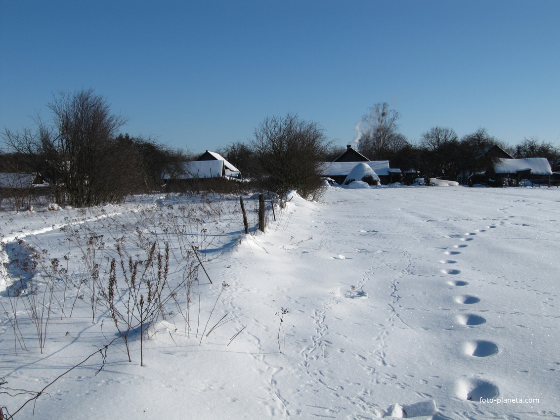 За огородами.